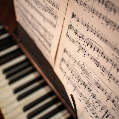 Looking down onto out of focus piano keys with sheet music in the forground